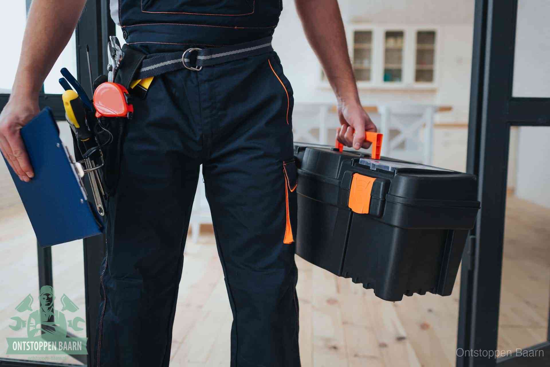 Een monteur met gereedschapsriem en klembord in een keuken, klaar om een transparante prijs voor het gootsteen ontstoppen in Baarn te geven