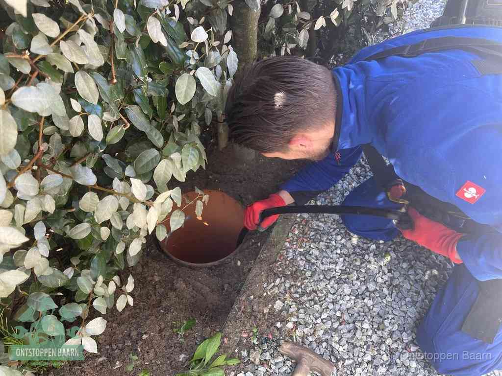 Monteur reinigt een rioolput met een slang, periodieke rioolreiniging in Baarn