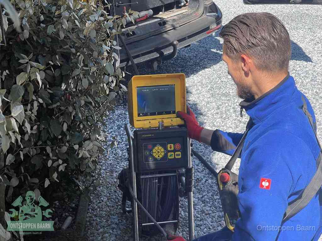 Monteur bedient een rioolinspectiecamera met monitor voor rioolinspectie in Baarn