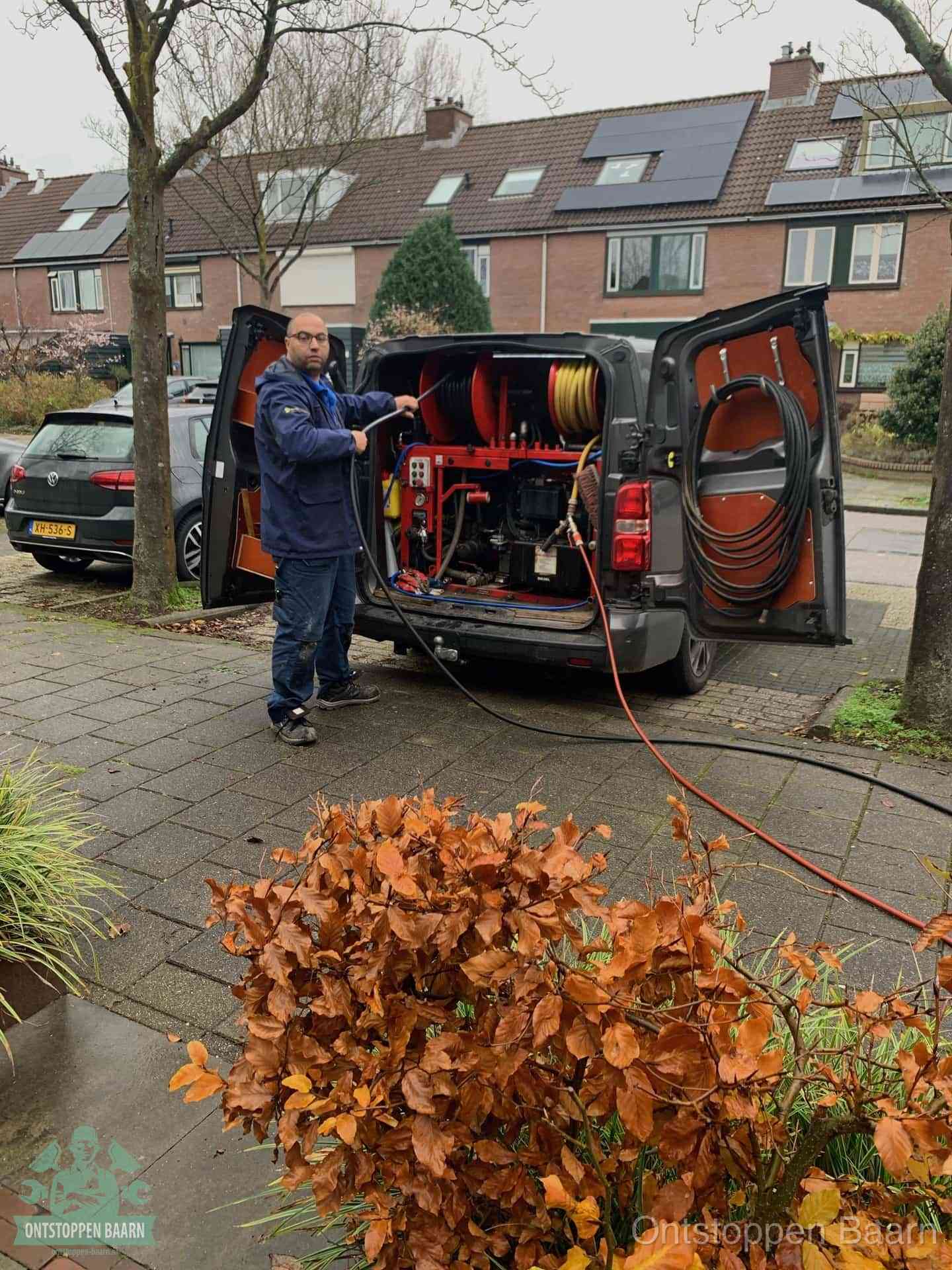 Monteur met rioolreinigingsbus levert rioolservice in de wijk in Baarn