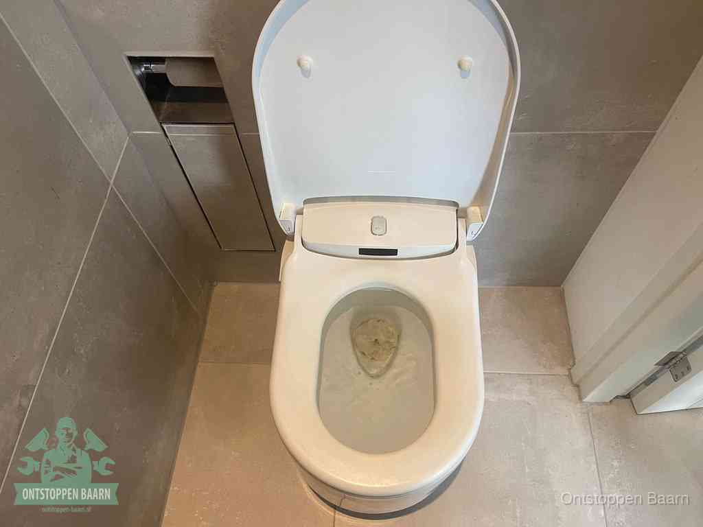 Een wit hangtoilet waarin een prop wc-papier op het water blijft drijven, een duidelijk signaal van een verstopte wc in Baarn
