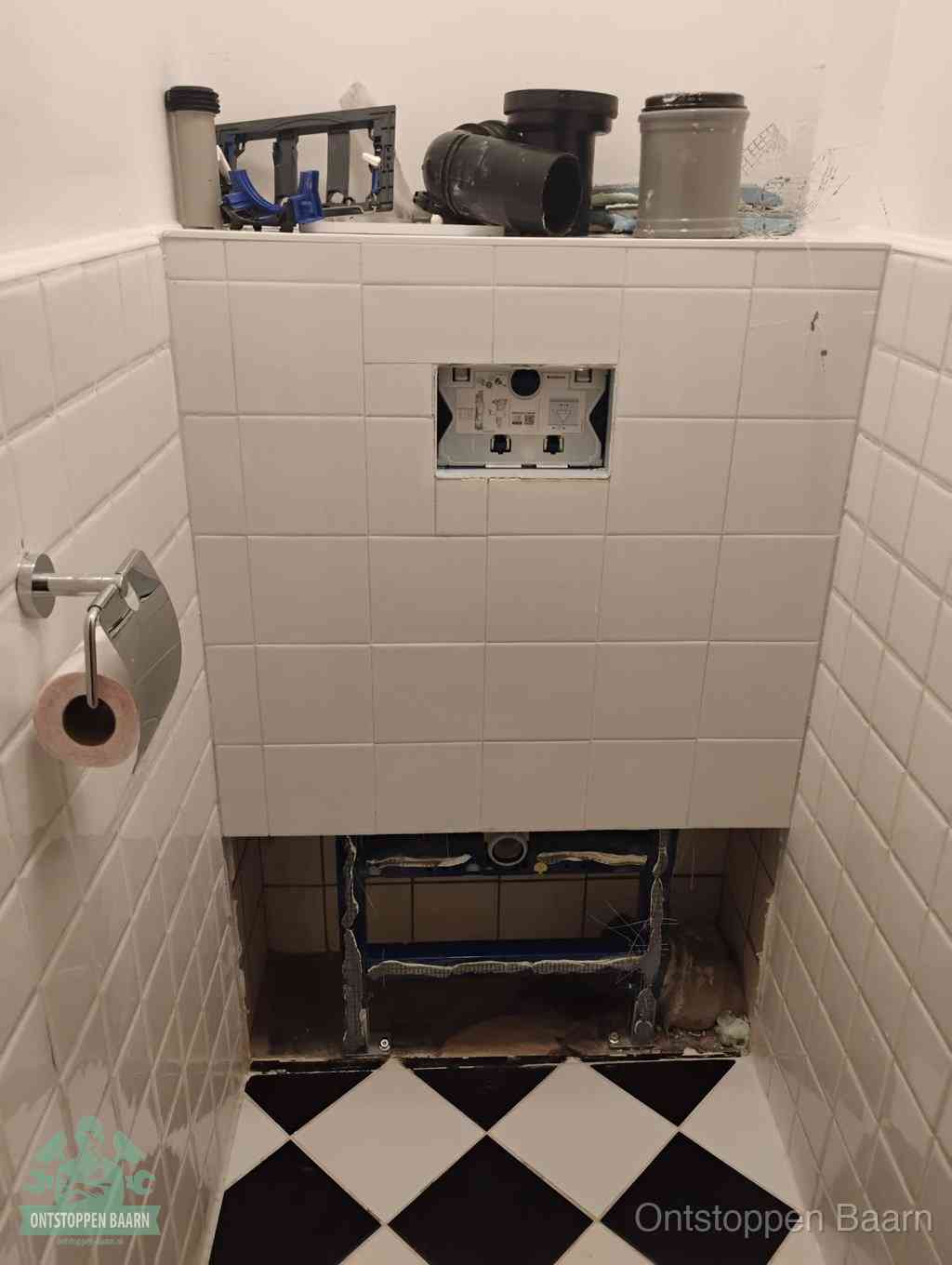 Een toiletruimte waar het hangtoilet en de inbouwreservoir-onderdelen zijn vrijgelegd voor onderhoud, periodiek nazicht voorkomt een wc-verstopping in Baarn