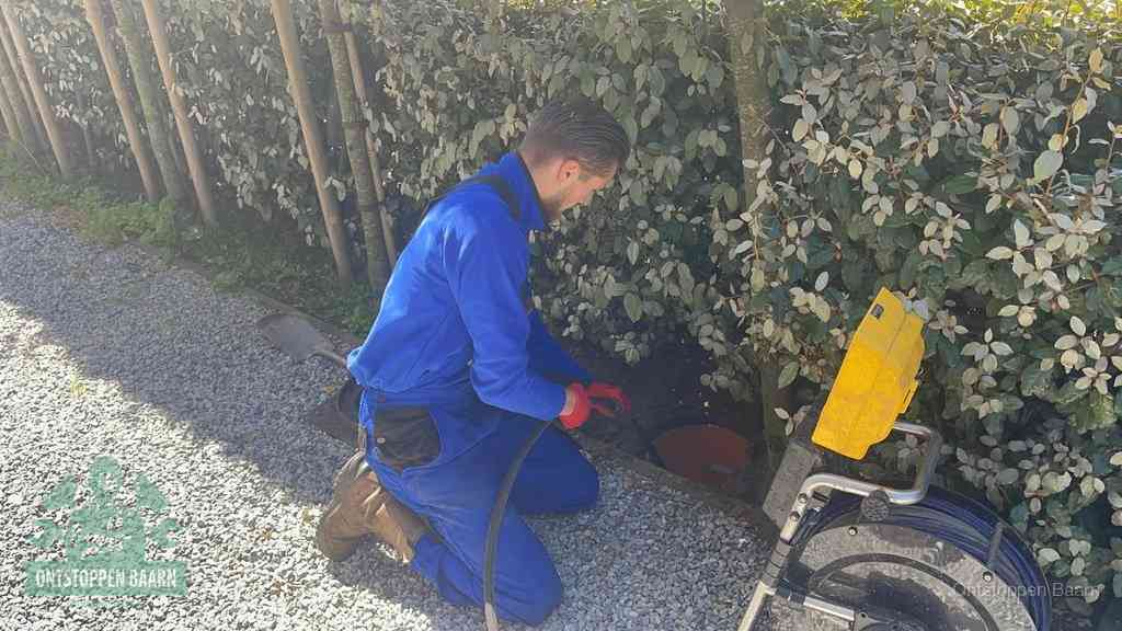 Monteur aan het werk bij een rioolput, de werkwijze voor riool ontstoppen in Baarn