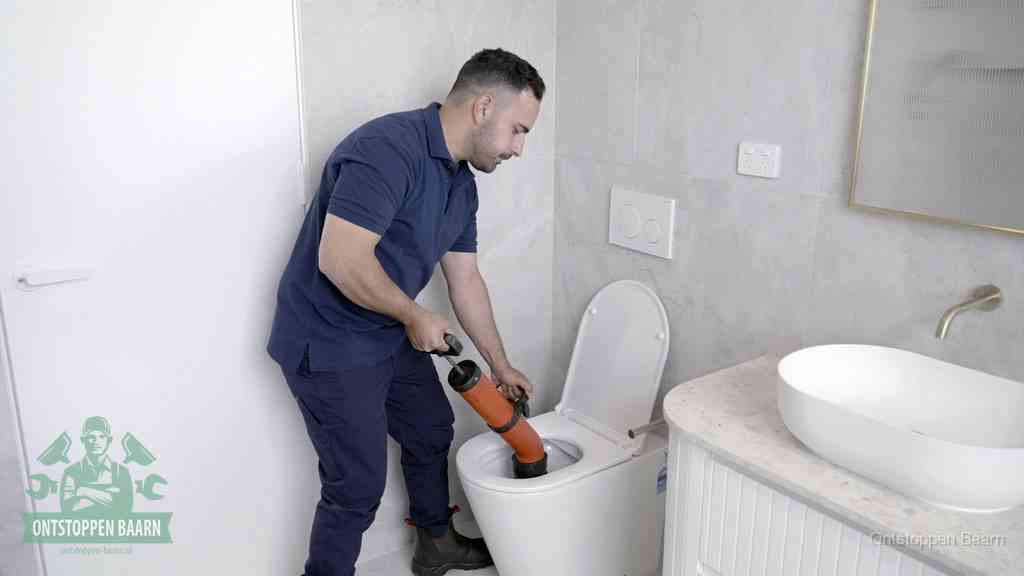 Een monteur gebruikt een handmatige perspomp (toiletontstopper) op een wandcloset tijdens het professioneel wc ontstoppen in Baarn